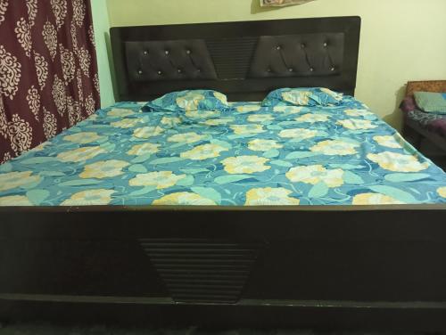 a bed with a blue bedspread with flowers on it at ram sadan in Ayodhya