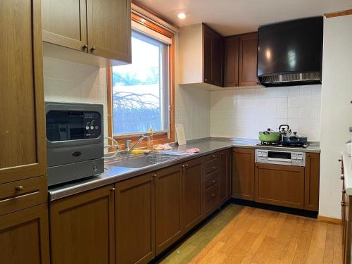 a kitchen with wooden cabinets and a sink and a window at 富士の屋河口湖 in Fujikawaguchiko