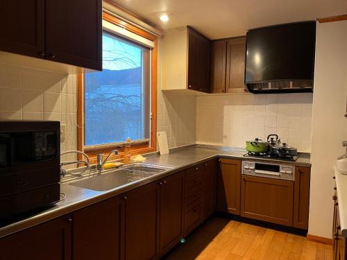 a kitchen with a sink and a stove and a window at 富士の屋河口湖 in Fujikawaguchiko