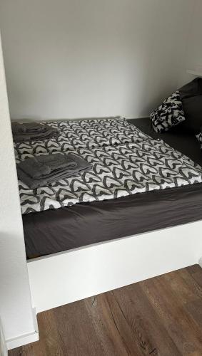 a bed with a black and white comforter on it at FeWo am Deich 4 in Bremerhaven