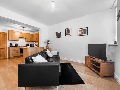 a living room with a black couch and a flat screen tv at Old Steamship Quarters in Whitby