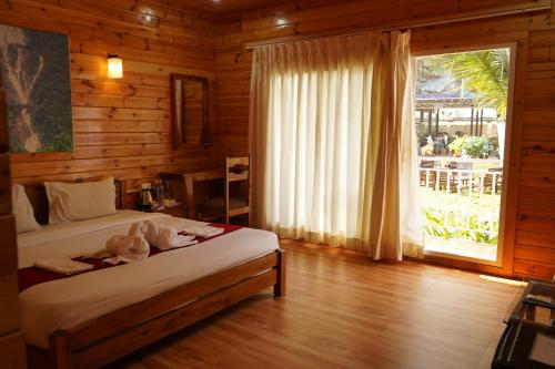 a bedroom with a bed and a large window at Shaan Coco Palms Beach Resort in Morjim