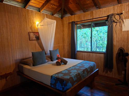 a bedroom with a bed with a teddy bear on it at Eco Lodge Village Temanoha in Paopao