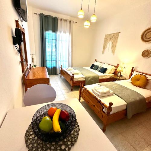 a room with two beds and a bowl of fruit on a table at Liberty Studio in Kallithea Halkidikis