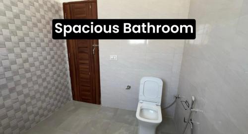 a bathroom with a white toilet in a stall at The Velvet Nest - Gurgaon - Luxurious Single Bedroom Private Villa with Garden in Gurgaon