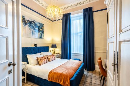 a bedroom with a bed with blue curtains and a chandelier at The Gifford in Edinburgh