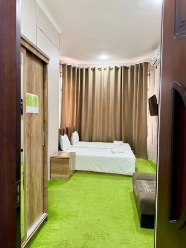 a bedroom with a white bed and green carpet at Chinor Garden Hotel - Free Airport Pick-up Yandex Go in Tashkent