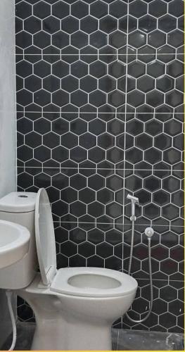 a bathroom with a toilet and a black tiled wall at Dhila Homestay Jalan Pasir Mas Rantau Panjang in Pasir Mas