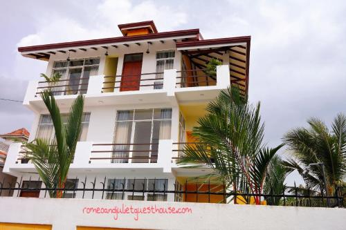 a white building with palm trees in front of it at Romeo and Juliet Guest House in Negombo