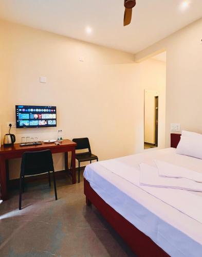 a bedroom with a bed and a desk with a computer at Hill View Heights Wayanad in Meppādi