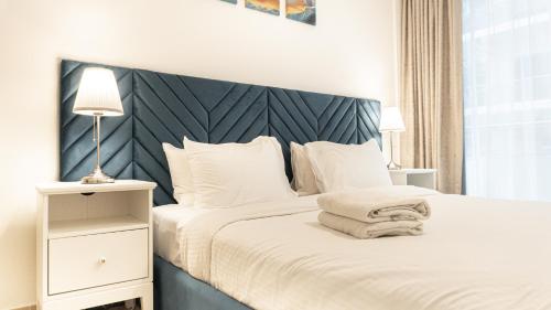 a bedroom with a white bed with a blue headboard at Elegant 1BHK Apartment with Courtyard View in Pacific Al Marjan Island in Ras al Khaimah