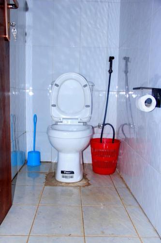 a bathroom with a toilet and a red basket at Tenzi BnB in Jinja