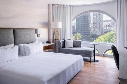 a bedroom with a bed and a chair and a window at Montreal Marriott Chateau Champlain in Montréal