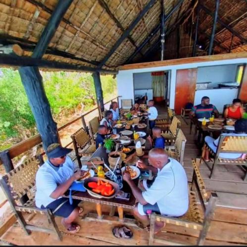 a group of people sitting at a table eating food at Wasini dolphin adventure in Shimoni