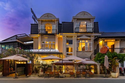 a hotel with tables and umbrellas in front of it at GreenMeadow Central Boutique in Da Lat