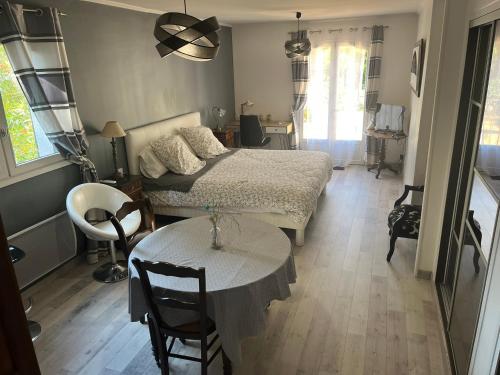 a bedroom with a bed and a table and a dining room at Grande Chambre meublee in Cornebarrieu