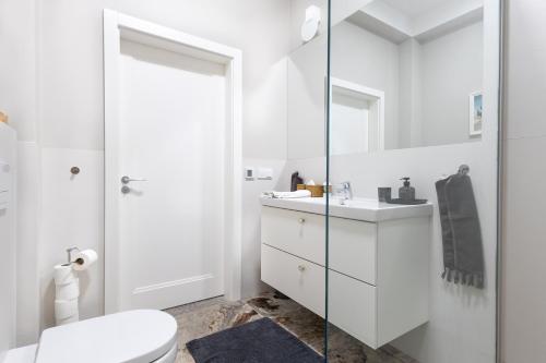 a white bathroom with a toilet and a sink at Baltivia Haus II in Gdynia