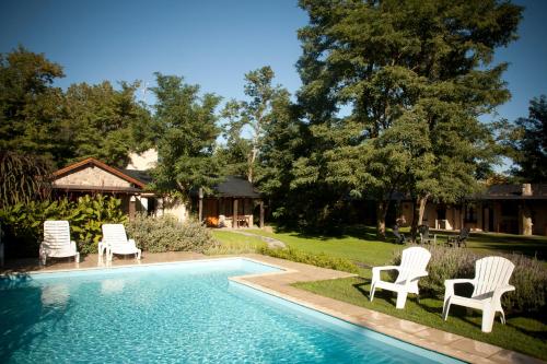 a swimming pool with chairs and a house at Las Retamas Apart Boutique in Sierra de la Ventana