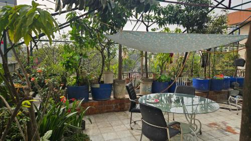 a patio with a glass table and chairs and plants at Kompass Sky Garden Home in Dhaka