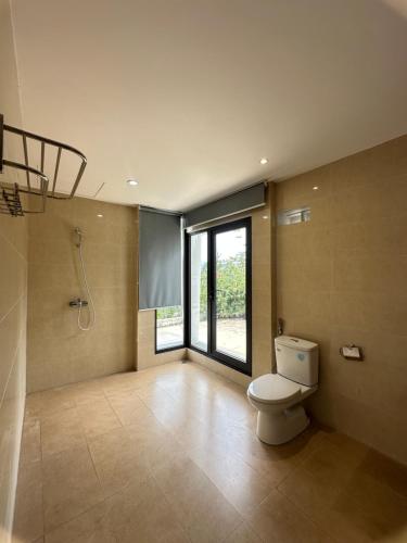 a bathroom with a toilet and a large window at Khu Nghỉ Dưỡng Ivory Villa Resort in Lương Sơn
