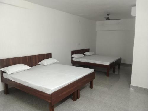 two beds are in a room with white walls at Akshay Hotel in Bikaner