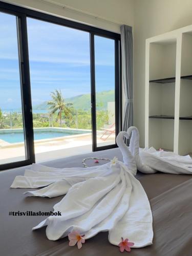 a bedroom with a bed with white sheets and a large window at Tris Villas ocean view in Kuta Lombok