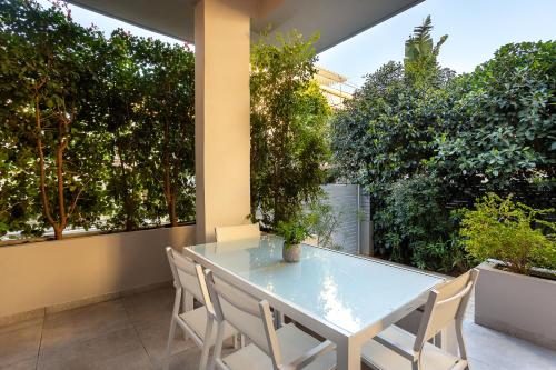 a glass table and chairs on a patio with trees at Elegant Garden Apartment Walk to Kalamata Center 2BR in Kalamata