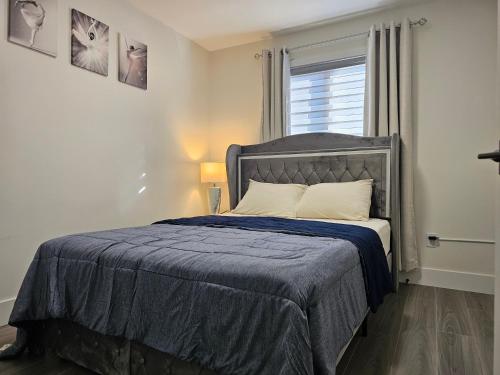 ein Schlafzimmer mit einem Bett mit einer blauen Decke und einem Fenster in der Unterkunft Elegant 3-bedroom Home Away From Home, Luxury Styled in St. John's