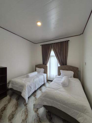 a bedroom with two beds and a window at d'Alvin Homestay 2 in Labuan Bajo