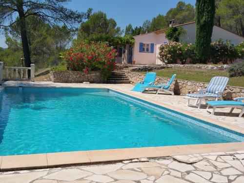 a swimming pool with blue chairs and a house at Modern Villa With Swimming Pool in Salernes France in Salernes