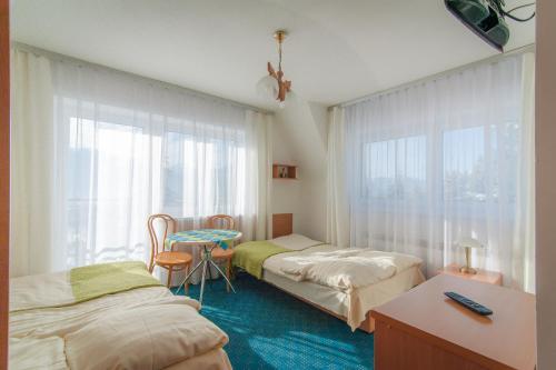a room with two beds and a table and a window at Nasz Dom in Kościelisko