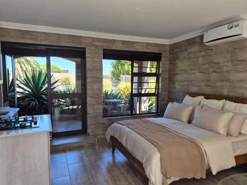 a bedroom with a bed and a kitchen with windows at Somerset Garden Studio in Somerset West