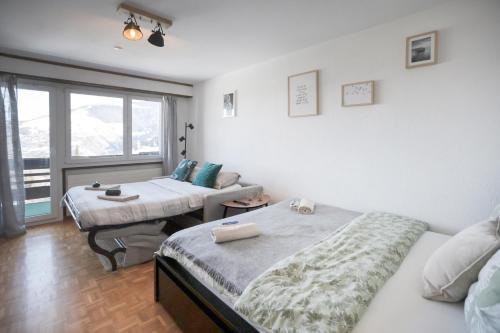 a bedroom with two beds and a window at Le Cleuson - centré avec vue in Nendaz