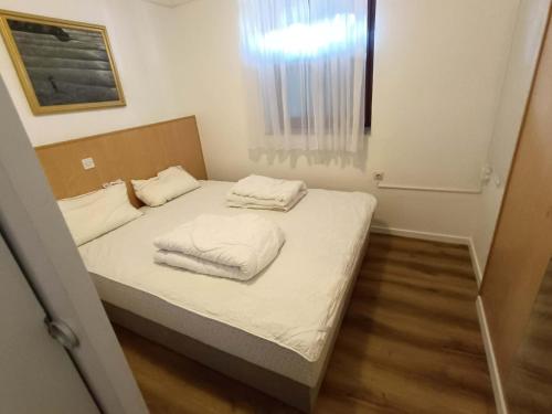 a small bedroom with a bed with two towels on it at Terme Čatež - Family apartments with pool tickets in Čatež ob Savi