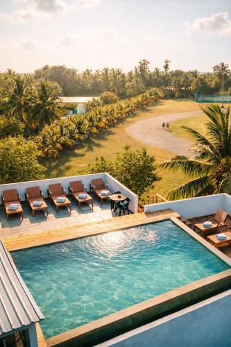 a swimming pool with chairs and a view of a beach at Cozy Roots Fuvahmulah in Fuvahmulah