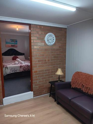 a bedroom with a brick wall and a clock on a wall at The Flat 28B on Ordnance in Lithgow
