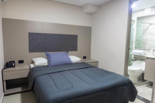 a bedroom with a bed with a blue pillow on it at NOVA Apartahotel in Medellín