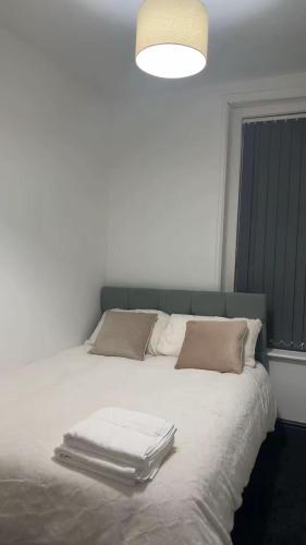 a bed with white sheets and pillows and a light at PLUS Properties Westport 2 in Stoke on Trent