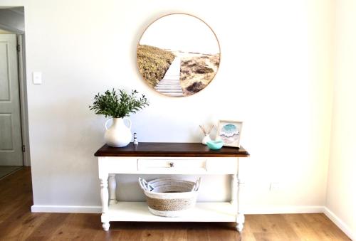 a mirror on a wall above a white console table at Goolwa Blue Escape - Beach Spacious Wi-fi in Goolwa