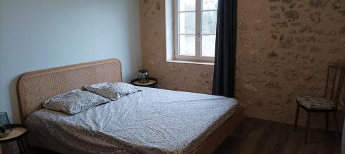 a bedroom with a bed and a window at Charme et tranquillité au cœur du Périgord in La Rafigne