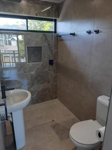 a bathroom with a shower and a toilet and a sink at 9 at Sea in Great Brak River