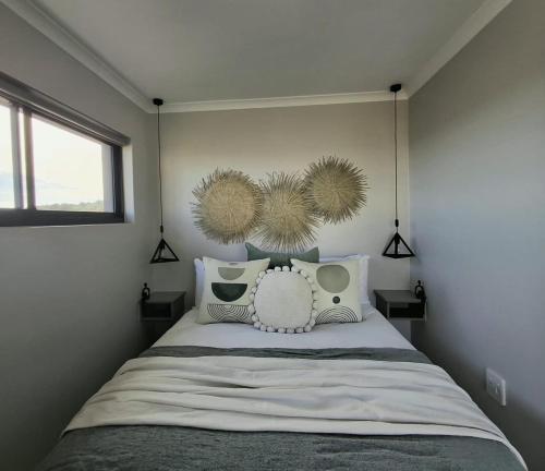 a bedroom with a bed with pillows and a window at 9 at Sea in Great Brak River
