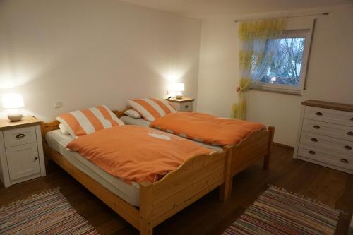 a bedroom with a bed with orange sheets and a window at Auszeit in Limbach