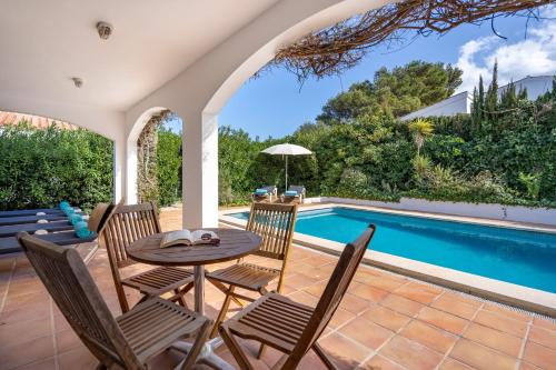 a patio with a table and chairs next to a swimming pool at Villa Sea Garden Holidays by 3VILLAS in Port d'Addaia