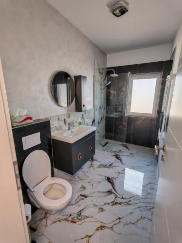 a bathroom with a marble floor with a toilet and a sink at Dream Home in Giroc
