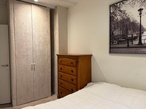 a bedroom with a bed and a wooden dresser at Appartement in Stadsdeel West in Amsterdam
