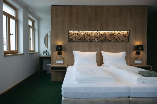 a bedroom with a large white bed and two windows at Grünbauer - Der Landgasthof in Reuth bei Erbendorf