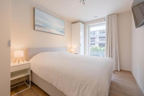 a bedroom with a white bed and a window at The Captainhouse in Nieuwpoort