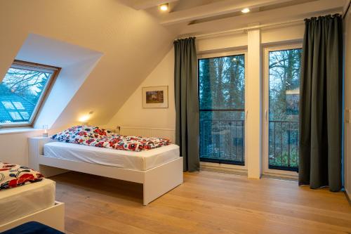 a bedroom with a bed and large windows at FeWo-Tannenriede in Braunschweig