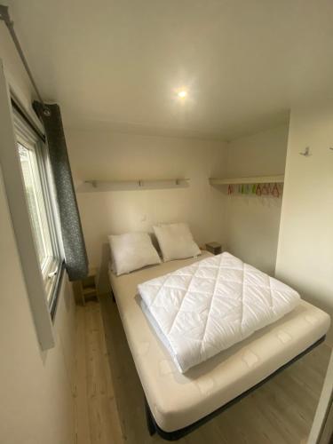 a white bed in a room with a window at l'impasse de la tranquillité in Pont-Aven